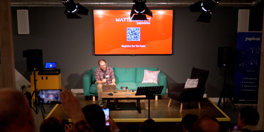 Connell Gauld sits on a sofa with a presentation in the background asking people to sign up to our mattercraft beta.
