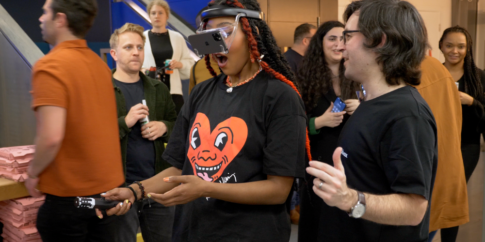 A young woman is wearing the Zapbox headset and using the controllers she looks amazed at the mixed reality she is seeing.
